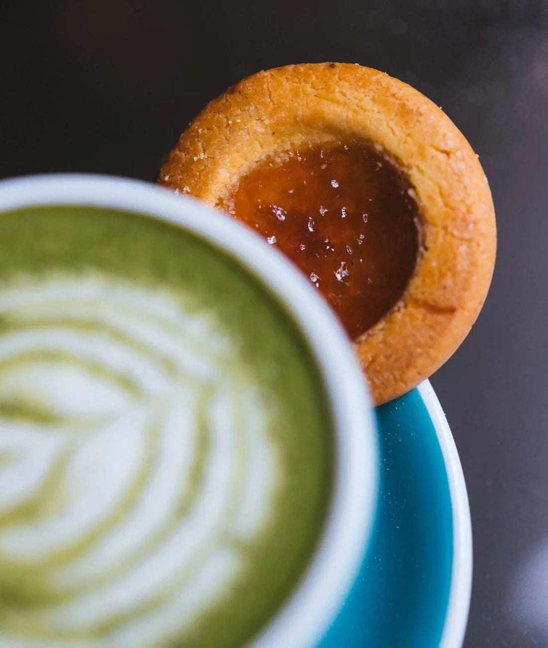 Matcha mélangé à du lait dans une tasse, accompagné d'un biscuit à la confiture