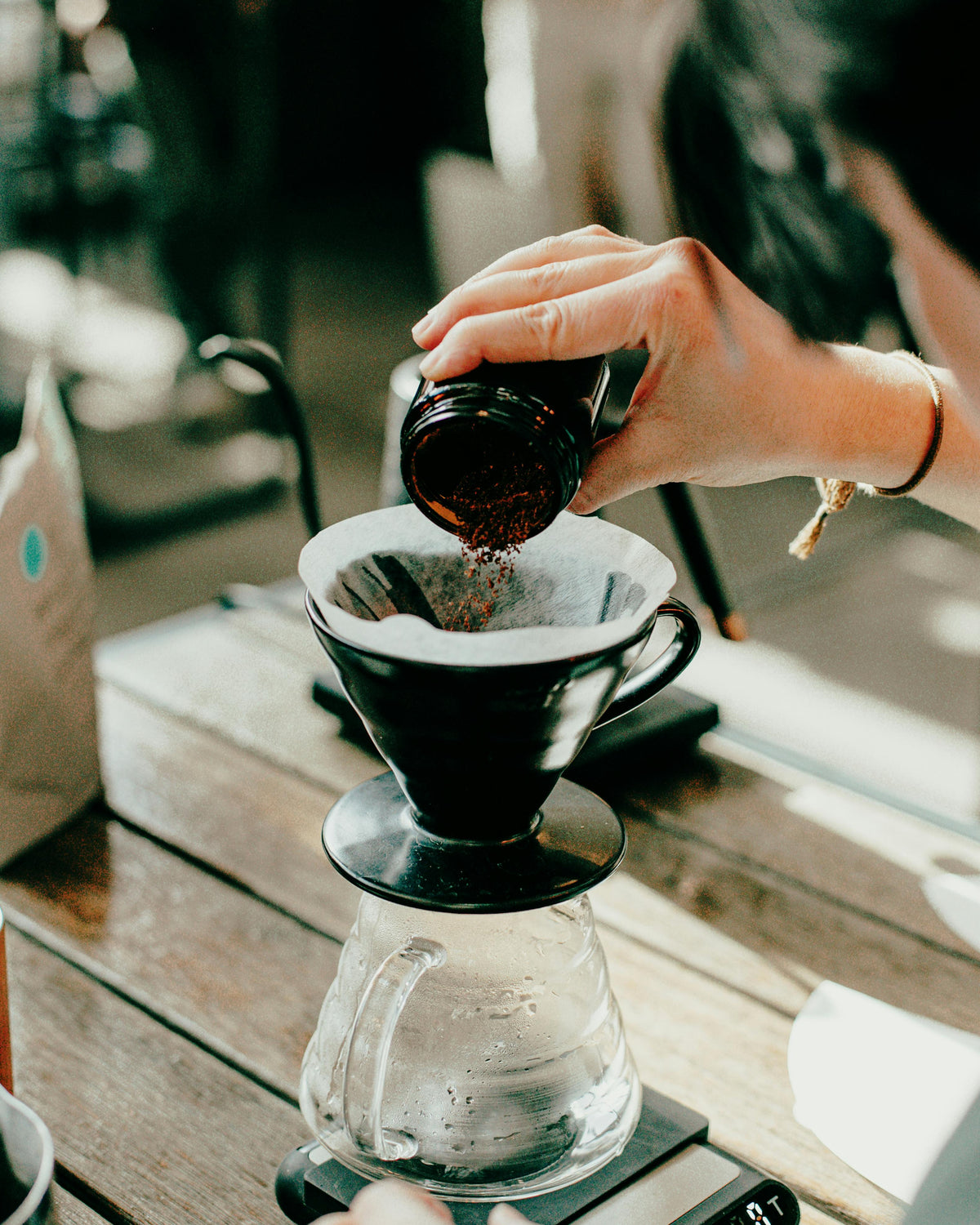 Un individu verse du café fraîchement moulu dans le porte-filtre d'une méthode douce