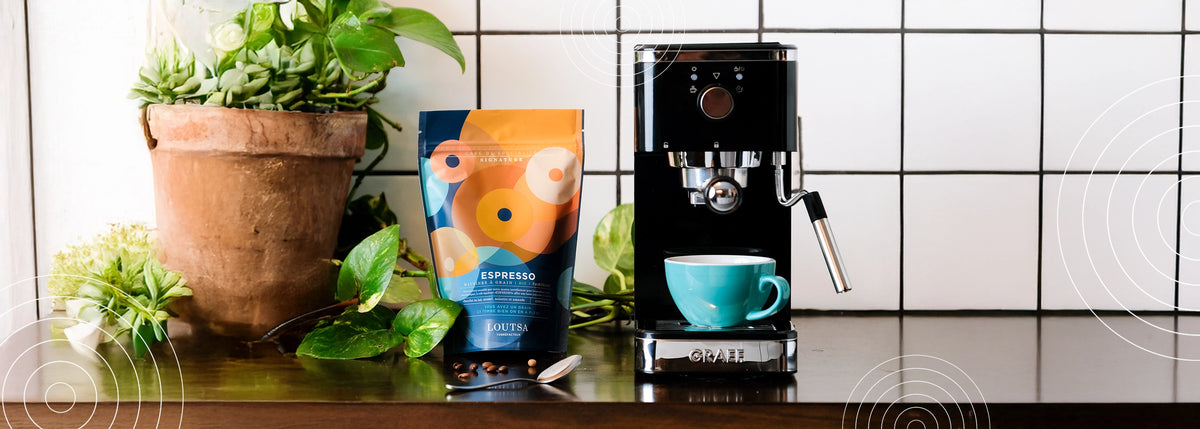 machine à café sur un plan de travail, avec un sachet de café ESPRESSO LOUTSA et une tasse 