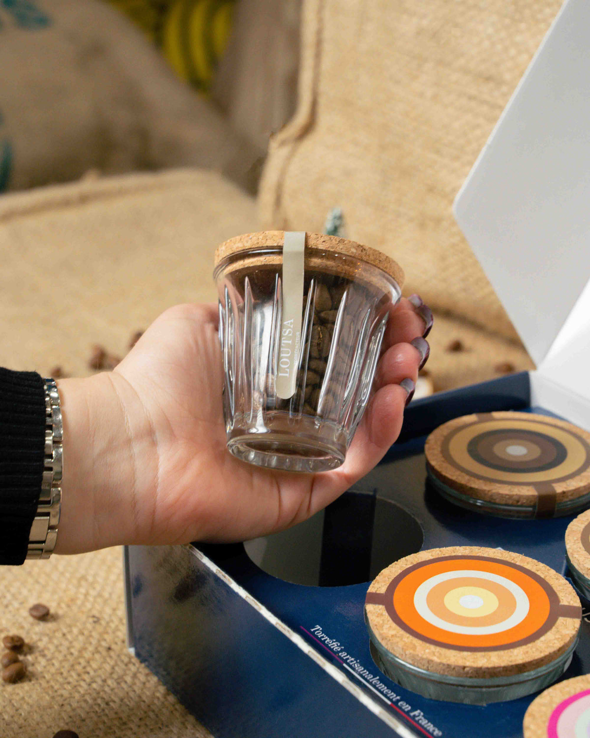 main saisissant un verre AL ROCHERE remplit de café de spécialité, fermé par un capuchon en liège