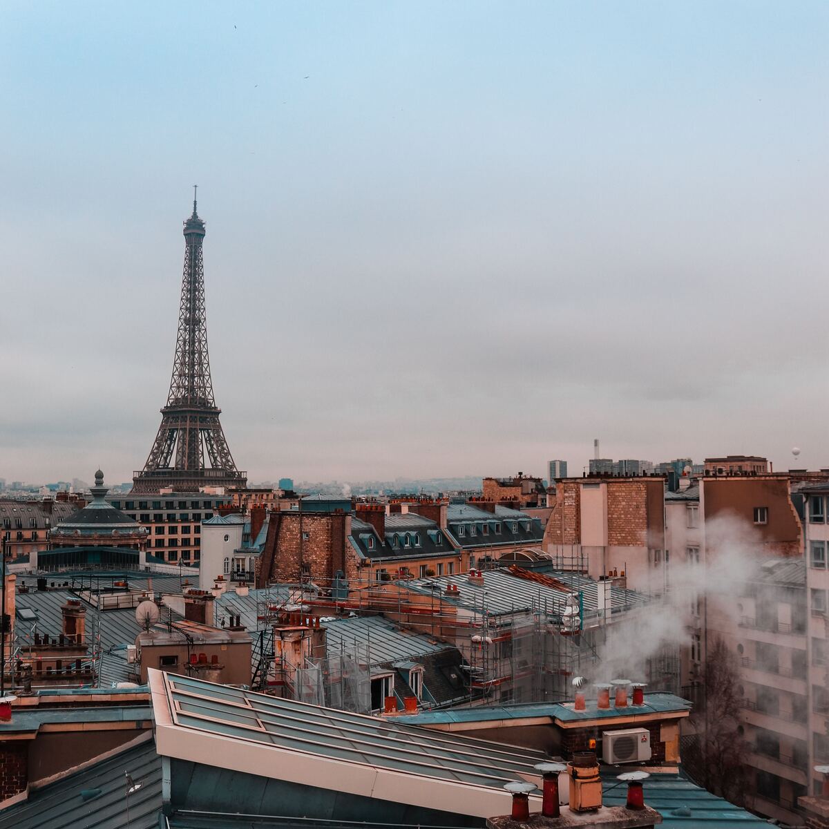 vue sur les toits de Paris, la Tour Eiffel et des cheminées fumantes 