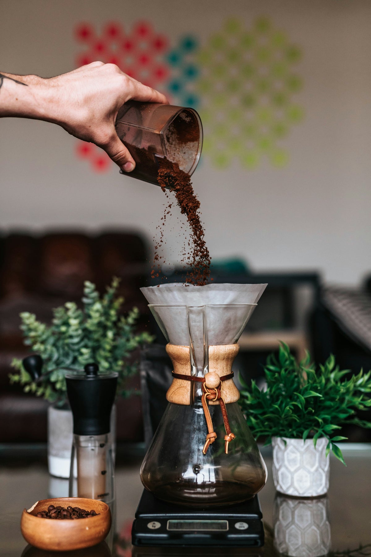 Un individu verse du café dans le filtre d'une chemex 6 tasses, posée sur une balance